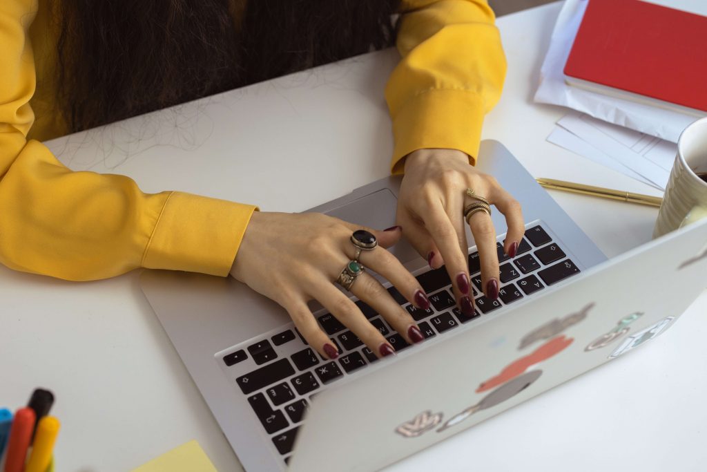 woman's hands with colorful rings on keyboard